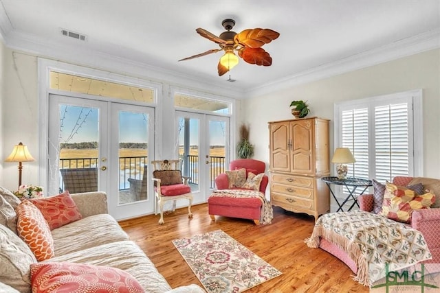 living area with visible vents, light wood finished floors, ceiling fan, french doors, and crown molding