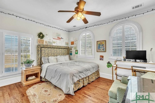bedroom featuring visible vents, baseboards, wood finished floors, and multiple windows