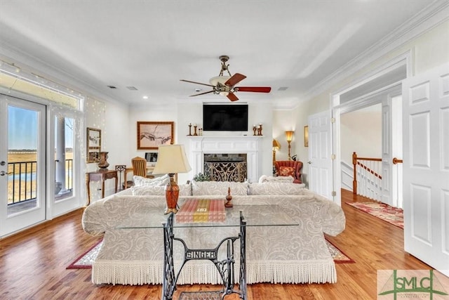 living room featuring visible vents, ornamental molding, a ceiling fan, wood finished floors, and a fireplace