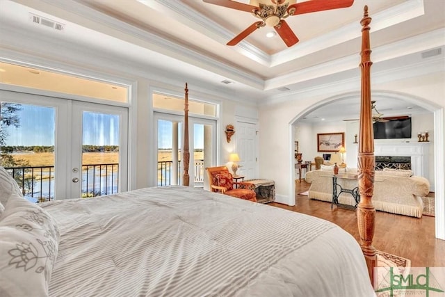 bedroom featuring a tray ceiling, access to outside, french doors, and visible vents