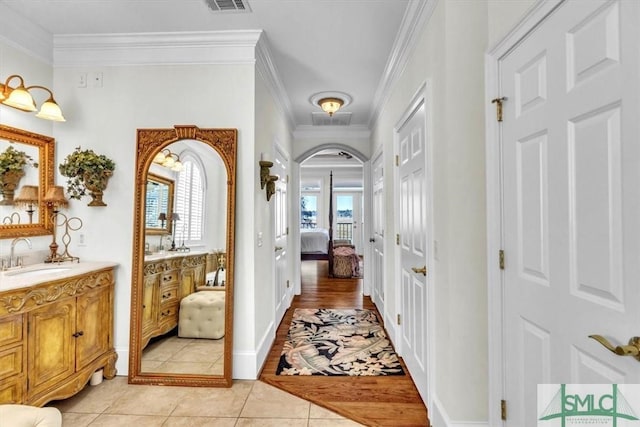 hall featuring arched walkways, light tile patterned floors, a healthy amount of sunlight, and a sink