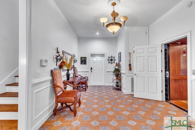 foyer entrance with a decorative wall, stairway, and a wainscoted wall