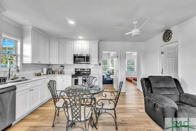 kitchen with open floor plan, white cabinetry, stainless steel appliances, and a sink