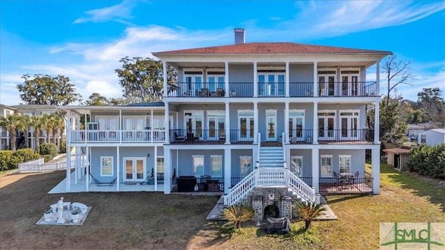 rear view of house with french doors, a chimney, stairway, a balcony, and a patio