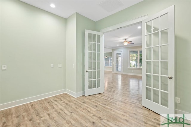 empty room featuring a ceiling fan, wood finished floors, baseboards, visible vents, and french doors