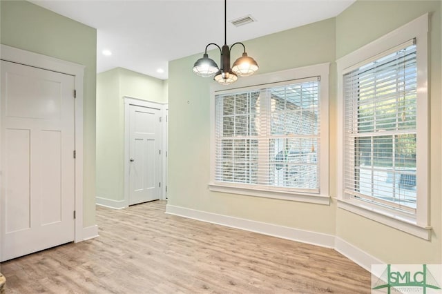 unfurnished dining area featuring a chandelier, visible vents, light wood-type flooring, and baseboards