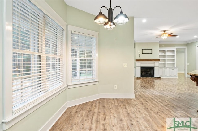 unfurnished dining area with baseboards, a fireplace with raised hearth, and light wood-style flooring