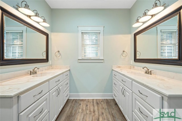 bathroom featuring two vanities, baseboards, and a sink