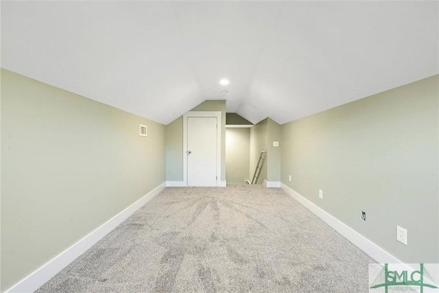 additional living space featuring lofted ceiling, light colored carpet, baseboards, and visible vents