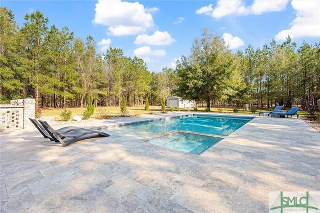 pool with a storage unit, a patio, an outbuilding, and an in ground hot tub