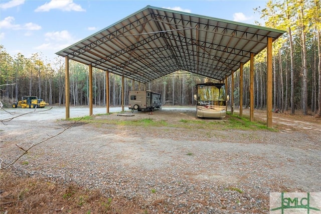 view of vehicle parking with a carport and a forest view