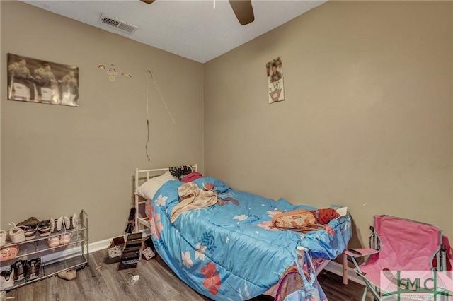 bedroom featuring visible vents, baseboards, wood finished floors, and a ceiling fan