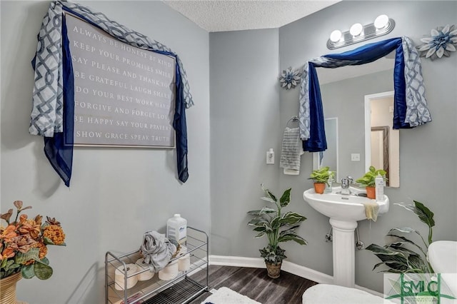 bathroom with a textured ceiling, baseboards, and wood finished floors