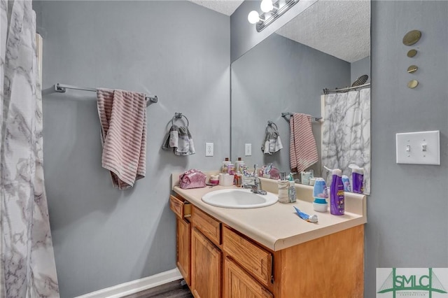 full bathroom with curtained shower, baseboards, a textured ceiling, and vanity