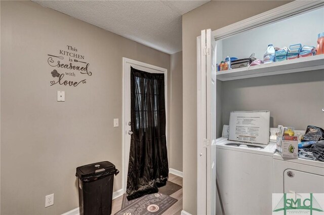 laundry room with baseboards, laundry area, wood finished floors, washer and dryer, and a textured ceiling