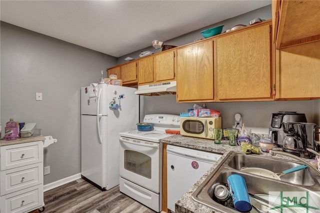 kitchen with white appliances, wood finished floors, a sink, light countertops, and under cabinet range hood