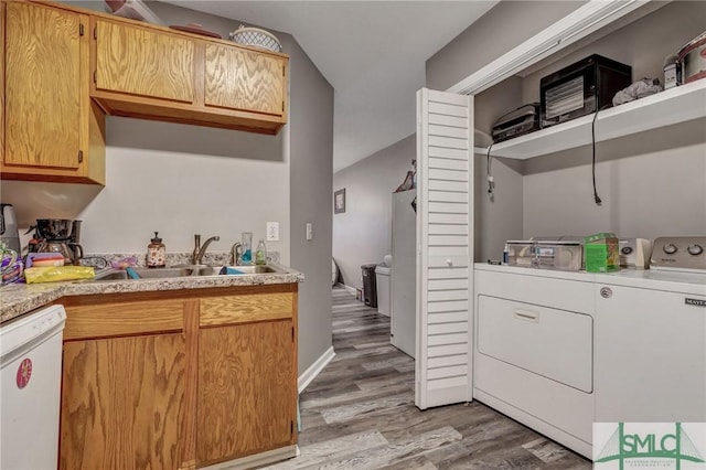 laundry area featuring laundry area, washing machine and clothes dryer, light wood-type flooring, and a sink