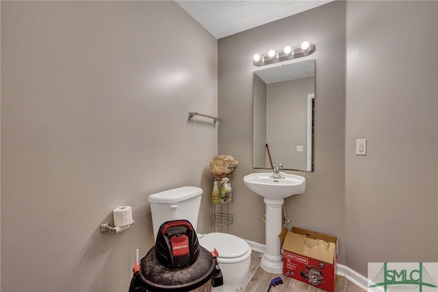 bathroom featuring toilet, wood finished floors, and baseboards