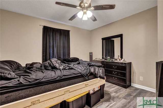 bedroom featuring ceiling fan, baseboards, a textured ceiling, and wood finished floors