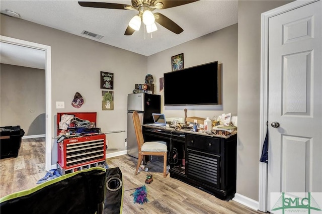 office space with visible vents, light wood-style flooring, baseboards, and ceiling fan