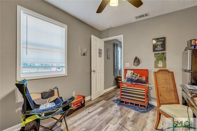 office area with ceiling fan, visible vents, baseboards, and wood finished floors