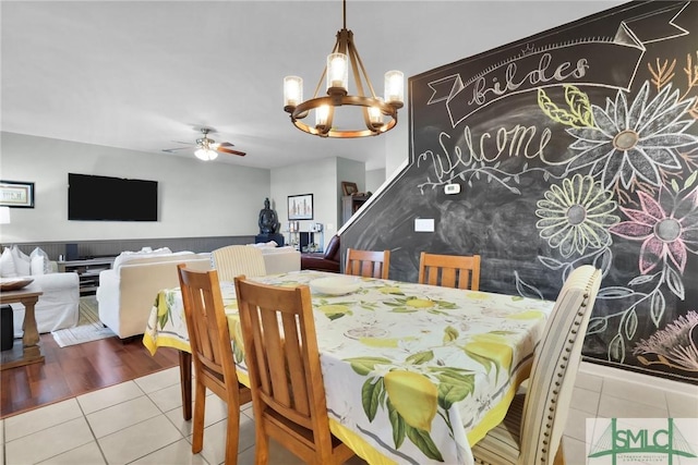 dining space with ceiling fan with notable chandelier and tile patterned flooring