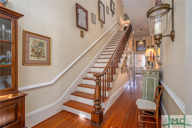 staircase with wainscoting and hardwood / wood-style flooring