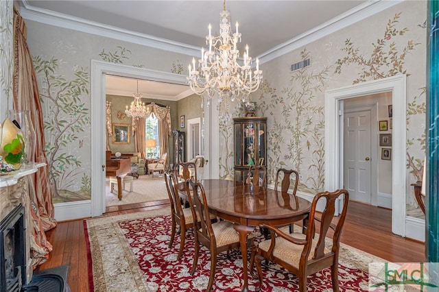 dining room with wallpapered walls, crown molding, an inviting chandelier, and wood-type flooring