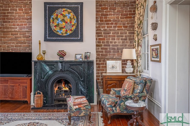 living area featuring a warm lit fireplace and hardwood / wood-style floors