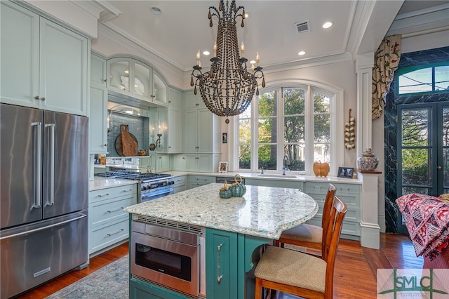 kitchen with visible vents, a sink, green cabinets, high quality appliances, and a wealth of natural light