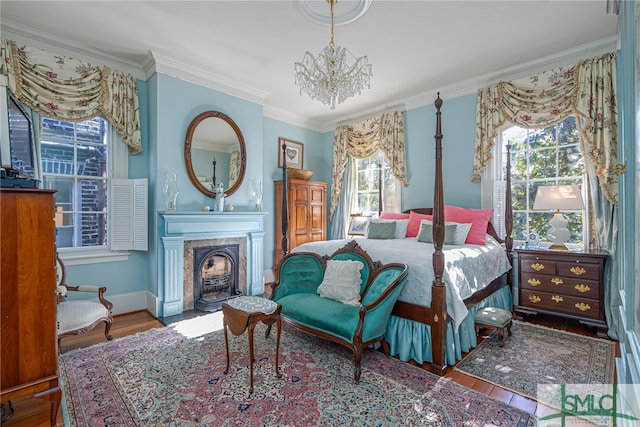 bedroom with a chandelier, crown molding, a high end fireplace, and wood finished floors