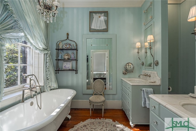 bathroom with baseboards, wood finished floors, ornamental molding, a freestanding tub, and vanity