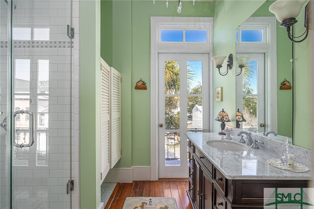 full bathroom with vanity, wood finished floors, a stall shower, and baseboards