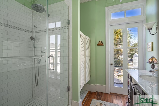 full bath featuring a stall shower, baseboards, wood finished floors, and vanity