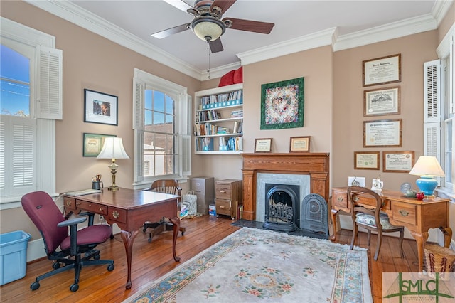 office with a fireplace with flush hearth, a ceiling fan, hardwood / wood-style floors, and crown molding