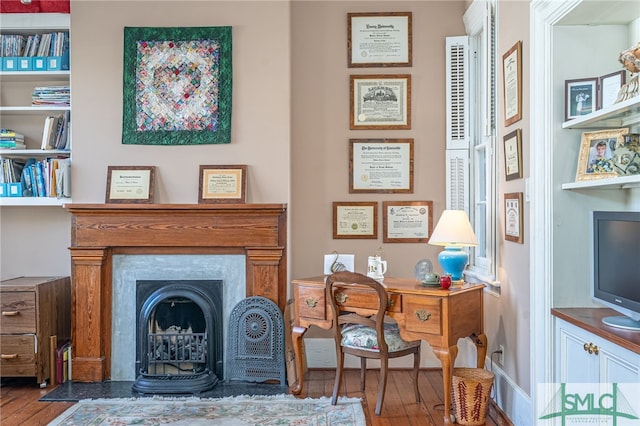 office space with a fireplace with flush hearth and wood finished floors