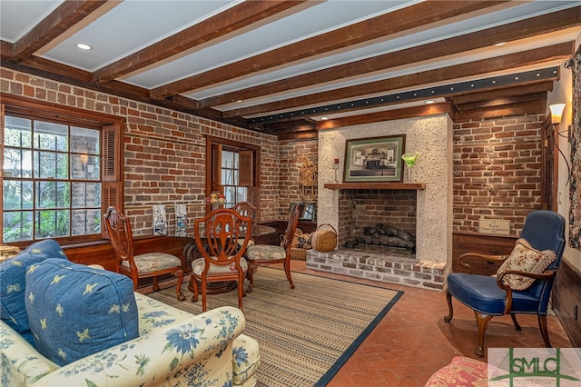 living area featuring brick wall, beam ceiling, recessed lighting, a fireplace, and brick floor