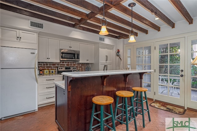 kitchen featuring decorative backsplash, brick floor, visible vents, and stainless steel appliances