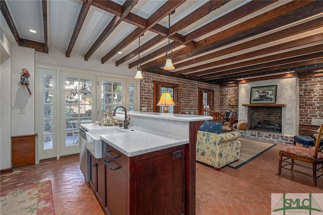 kitchen with open floor plan, brick floor, a wealth of natural light, and a sink