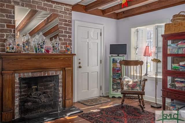 living room with beam ceiling, a brick fireplace, plenty of natural light, and wood finished floors