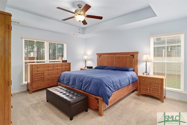 bedroom featuring visible vents, a raised ceiling, light colored carpet, and baseboards