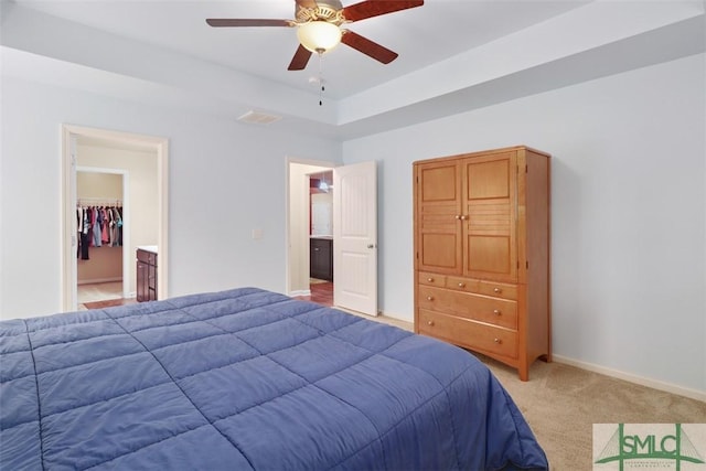 bedroom featuring light carpet, a ceiling fan, a raised ceiling, and baseboards