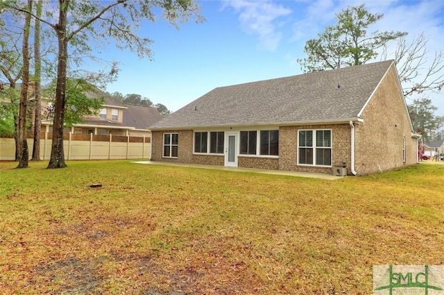 back of property with a yard, brick siding, and fence