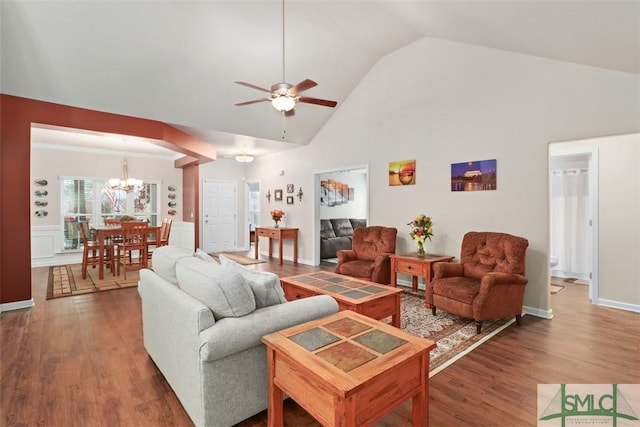 living room with high vaulted ceiling, wood finished floors, and ceiling fan with notable chandelier