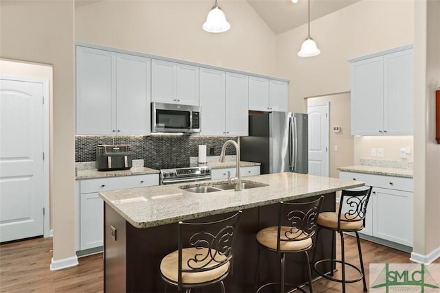 kitchen featuring backsplash, a breakfast bar area, appliances with stainless steel finishes, hanging light fixtures, and a sink