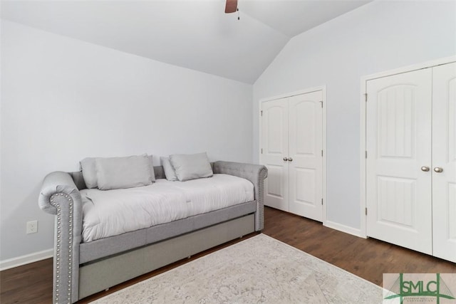 bedroom featuring lofted ceiling, baseboards, multiple closets, and dark wood-style flooring