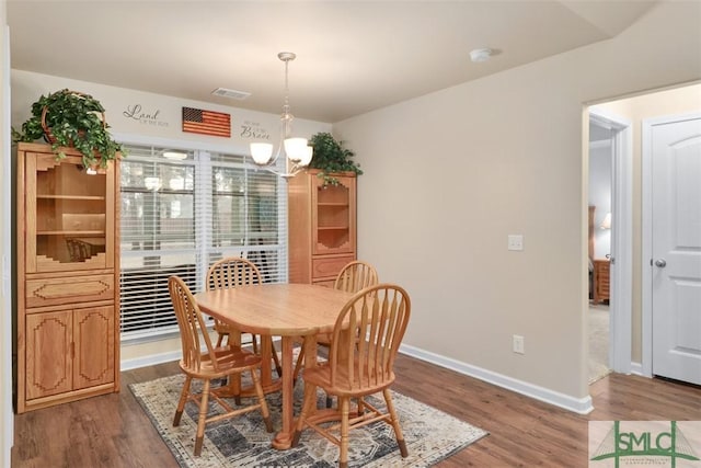 dining area featuring an inviting chandelier, wood finished floors, visible vents, and baseboards