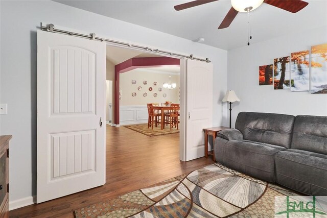 living room featuring ceiling fan, a barn door, and wood finished floors