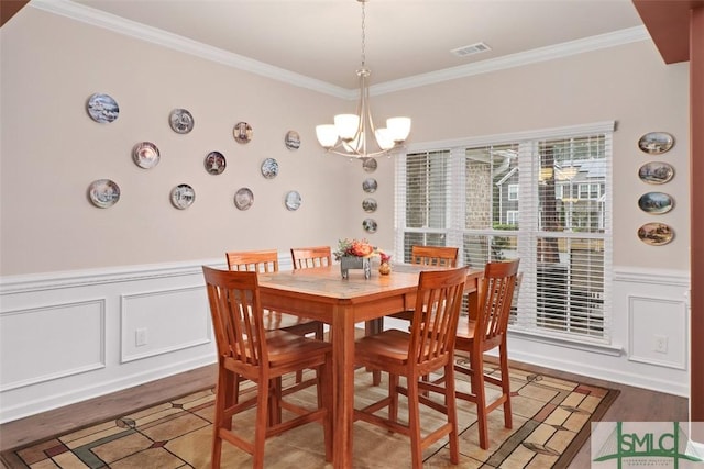 dining area featuring visible vents, ornamental molding, an inviting chandelier, and wood finished floors