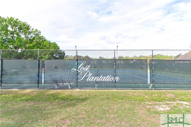 view of sport court featuring fence and a lawn